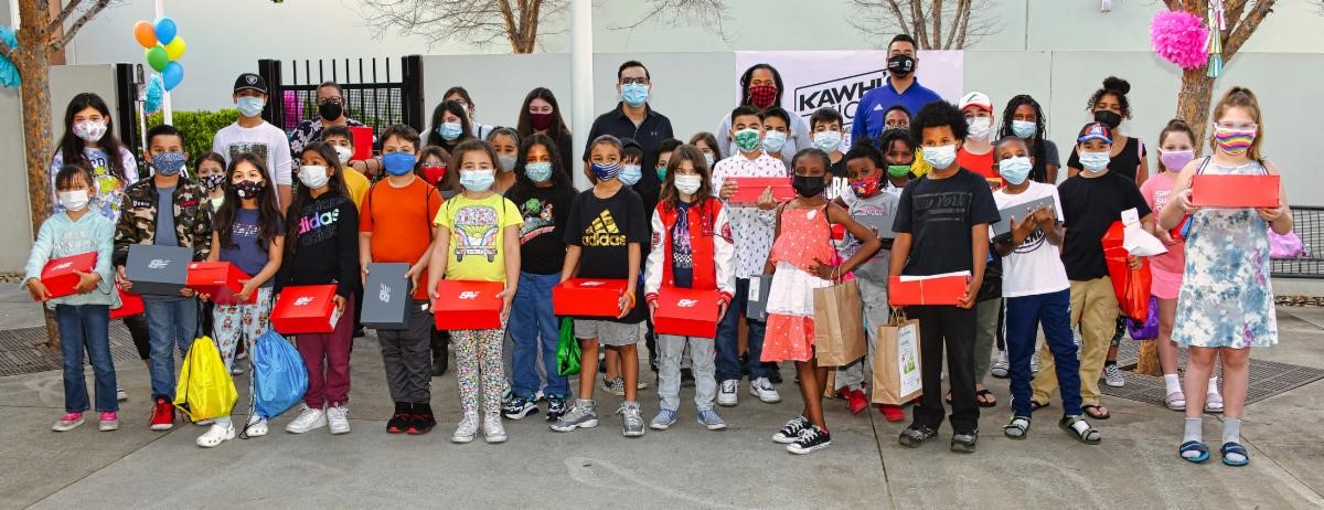 Moreno Valley children holding New Balance boxes.